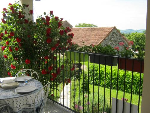 un balcon avec une table et une clôture avec des roses dans l'établissement La maison d'Ormancey, à Mont-Saint-Jean