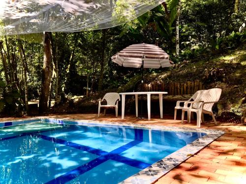 a table and chairs and an umbrella next to a swimming pool at Casa Quinta privada con piscinas Billar, Tejo, Jacuzzy climatizado, kiosco in La Vega