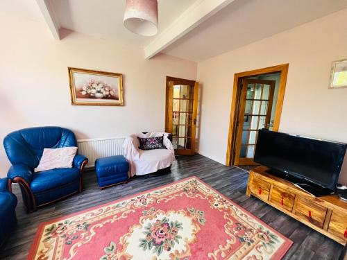 uma sala de estar com uma televisão de ecrã plano e cadeiras azuis em Park Road Holiday Home em Rosyth