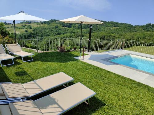 a backyard with a pool and chairs and an umbrella at Bricco - Bed&Breakfast in Murisengo