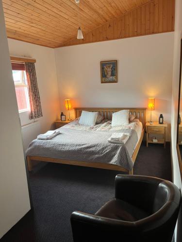 a bedroom with a bed and a chair in it at Engimyri Lodge in Akureyri