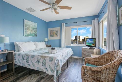 een blauwe slaapkamer met een bed en een televisie bij Five Palms Vacation Rentals- Daily - Weekly - Monthly in Clearwater Beach