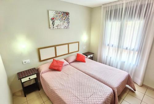 a bedroom with a bed with pink sheets and red pillows at HOSTAL RIGAU in Sant Feliu de Guixols