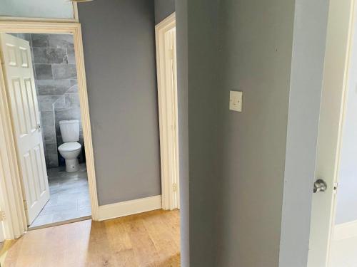 a bathroom with a toilet and a hallway with a mirror at 2nd floor shared flat near Bedford train station in Bedford