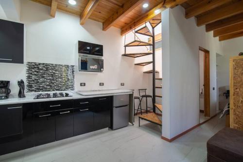 a kitchen with black cabinets and a spiral staircase at Ursus, Mi casita en México in Mexico City