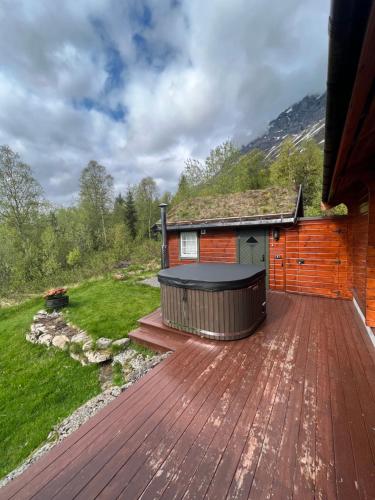 a hot tub on a deck next to a house at Cabin near the lake in Årset