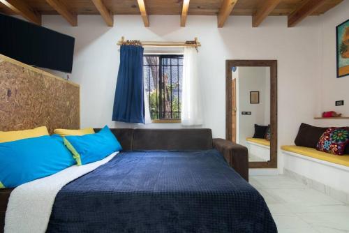 um quarto com uma cama com almofadas azuis e amarelas em Ursus, Mi casita en México em Cidade do México