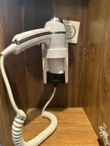 a hair dryer with a cord plugged into a wall at Hôtel Restaurant Clément ADER in Muret