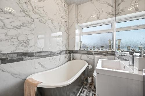 ein weißes Badezimmer mit einer Badewanne und einem Waschbecken in der Unterkunft Wembley Luxury Residence- Opulence House in London