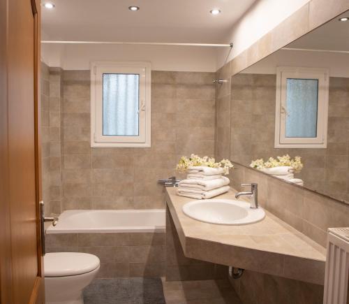 een badkamer met een wastafel, een bad en een toilet bij Nest Aegina Apartments in Perdhika