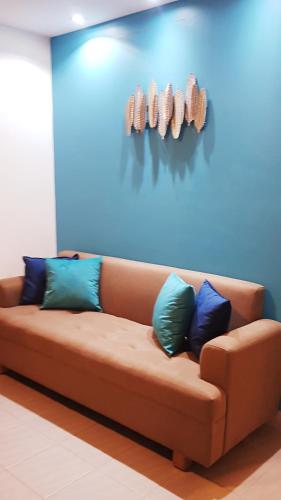 a brown couch with pillows on a blue wall at Villa del Mar Departamento 1 I in Salinas