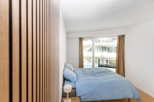 a bedroom with a bed and a large window at Lys 3 værelses lejlighed med 26 m2 sydvendt altan in Aarhus