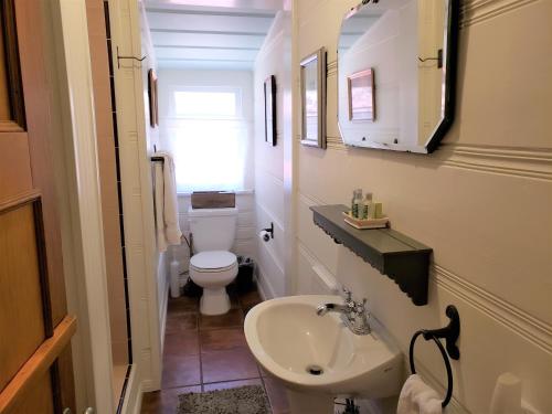 Un baño pequeño con lavabo e inodoro. en A Sweet Pine Cabin - Adorable retro home in a peaceful residential neighborhood, en Big Bear City