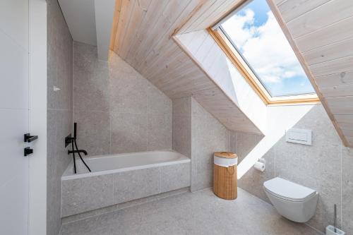 uma casa de banho com uma banheira e uma clarabóia em Luxury 2 BD Apartment with terrace by Hostlovers em Kaunas