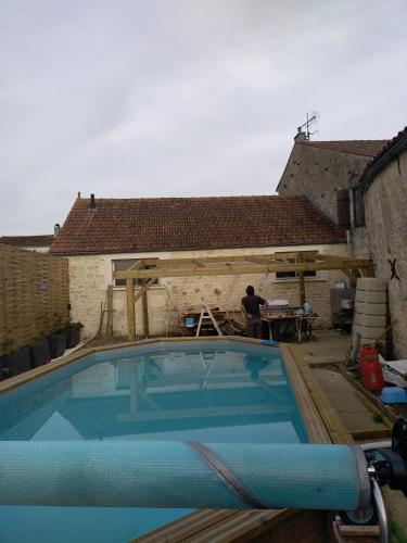 Um homem está a trabalhar numa casa com piscina. em Chez cococuisine em Les Nouillers