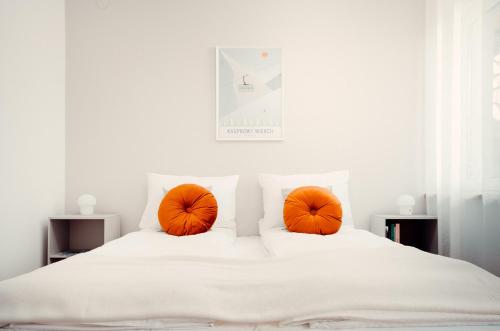 two orange pillows on a bed with white sheets at Giewont Mountain View Apartment in Zakopane