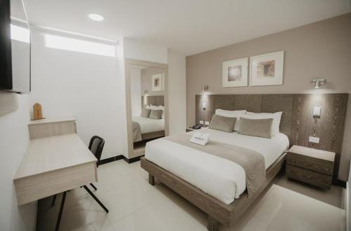 Una habitación de hotel con una cama grande y un escritorio. en Hotel Marrakech Cali, en Cali