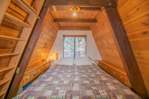 a bedroom in a wooden cabin with a bed and a window at A-Frame of Mind - Nice cozy cabin great view to the outdoors and peaceful in Big Bear City