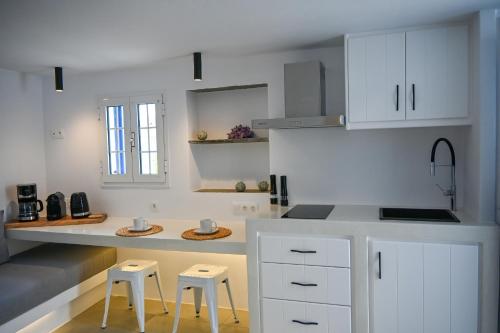 mikro Thama في Kámbos: مطبخ مع دواليب بيضاء وكراسي في الغرفة