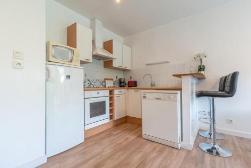 Il comprend une cuisine équipée d'un réfrigérateur blanc et d'une chaise noire. dans l'établissement Appartement Saint Goustan : Vue sur la rivière, à Auray