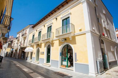 un edificio amarillo con balcones en una calle en Odissea Residence e Rooms, en Santa Maria di Castellabate