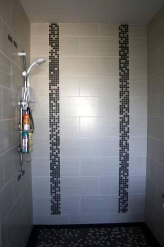 a bathroom with a shower with a tiled wall at Baile Go Deo. in Falcarragh