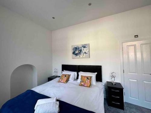 een slaapkamer met een bed met witte lakens en kussens bij Spacious and Elegant Apartment in Birmingham