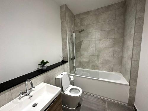 een badkamer met een toilet, een bad en een wastafel bij Spacious and Elegant Apartment in Birmingham