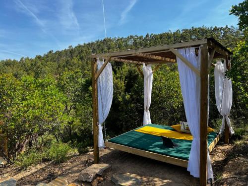 a canopy bed in a field with trees in the background at Costa Vicentina Sky View in Rogil