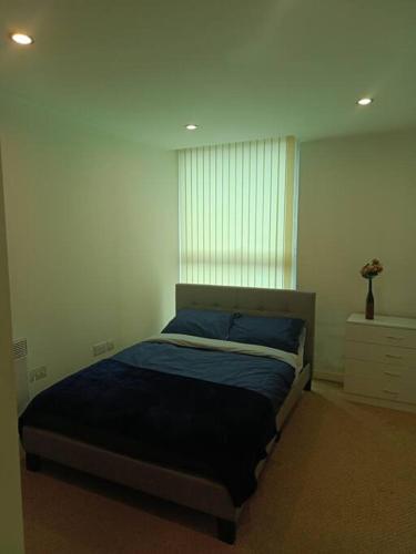 a bedroom with a bed with blue sheets and a window at A Home in the City. in Sheffield