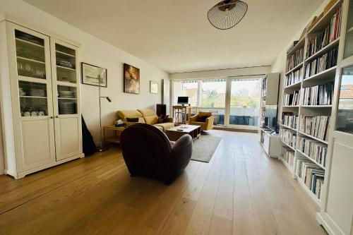 a living room with a chair and a couch and bookshelves at Stylish and Bright Apartment on the Outskirts of Bordeaux in Bordeaux