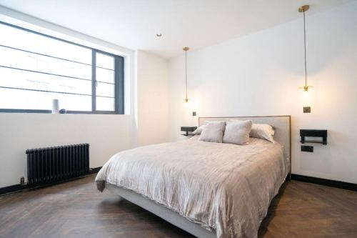 a white bedroom with a bed and a large window at Chic City Centre Penthouse in Leicester