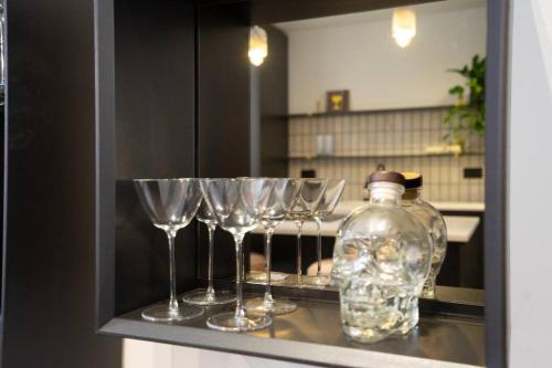 a group of wine glasses and a bottle on a shelf at Chic City Centre Penthouse in Leicester