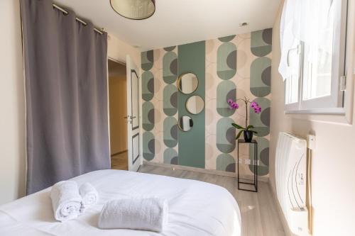 Les Lilas Confort & Nature في فولفيك: غرفة نوم بسرير ابيض وجدار اخضر وابيض