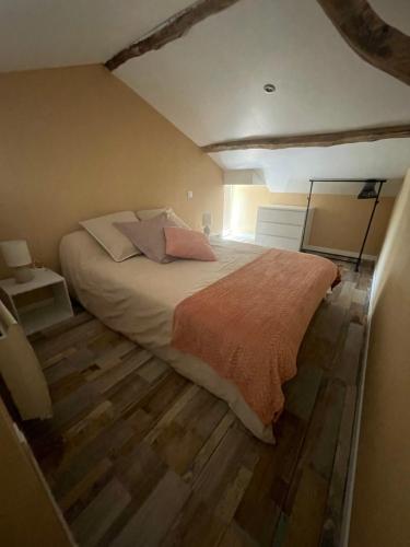 sypialnia z dużym łóżkiem i drewnianą podłogą w obiekcie L'Abeille SAS le jardin de Messie w mieście Beaumont