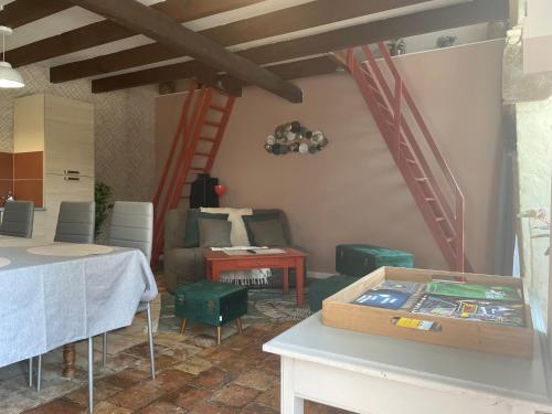 ein Wohnzimmer mit einem Tisch und einer Treppe in der Unterkunft L'Abeille SAS le jardin de Messie in Beaumont