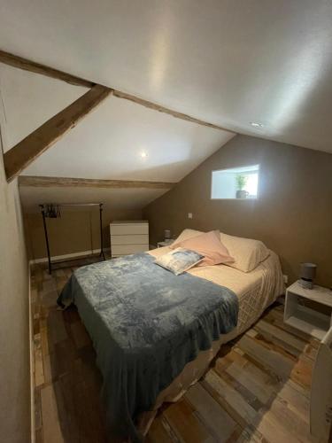 sypialnia z dużym łóżkiem na poddaszu w obiekcie L'Abeille SAS le jardin de Messie w mieście Beaumont