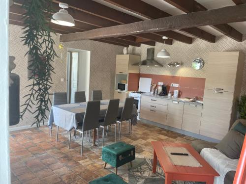 eine Küche und ein Esszimmer mit einem Tisch und Stühlen in der Unterkunft L'Abeille SAS le jardin de Messie in Beaumont
