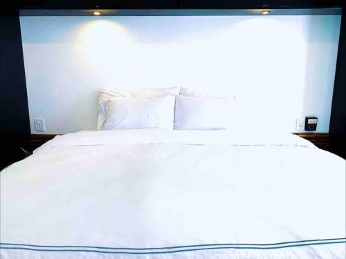uma cama com lençóis brancos e almofadas num quarto em Villa Ocean em Puerto Escondido