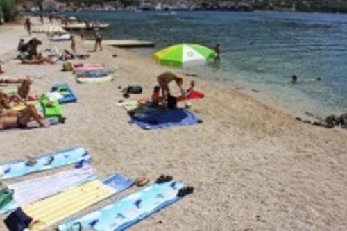 a group of people on a beach with umbrellas at Atraktivna kuća sa saunom i grijanim jacuzzijem in Cres