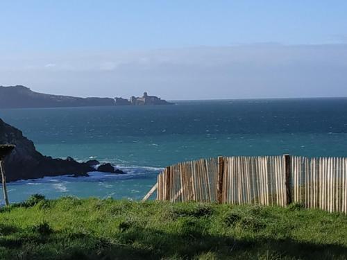 une clôture sur une colline à côté de l'océan dans l'établissement Mobile-home 4 pers vue mer, à Saint-Cast-le-Guildo