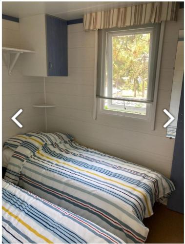 uma cama num pequeno quarto com uma janela em Mobile-home 4 pers vue mer em Saint-Cast-le-Guildo
