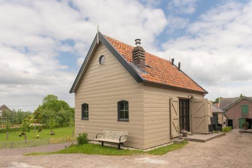 a small house with a bench in a yard at Vrijstaand huisje, dichtbij Kinderdijk in Oud-Alblas