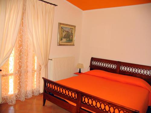 a bedroom with a large orange bed and a window at La Casa Dei Boschi in San Marino