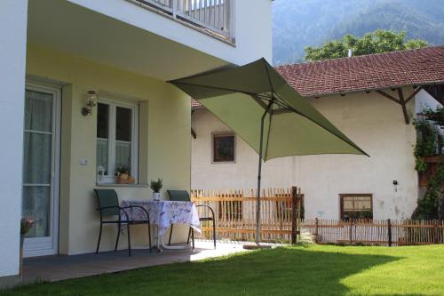 un patio con una mesa y una sombrilla verde en Gartnerhof, en Plaus