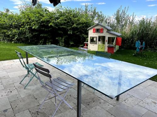 a glass table with two chairs and a play house at Haus am Hügel in Oberkühberg