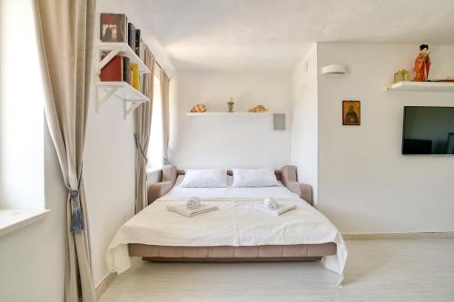 a small white bedroom with a bed and a tv at Eva's country house in Buljarica