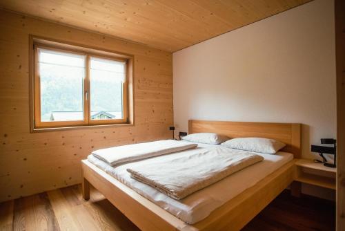 Cette chambre comprend un grand lit et une fenêtre. dans l'établissement Barbara's Ferienwohnungen, à Au im Bregenzerwald