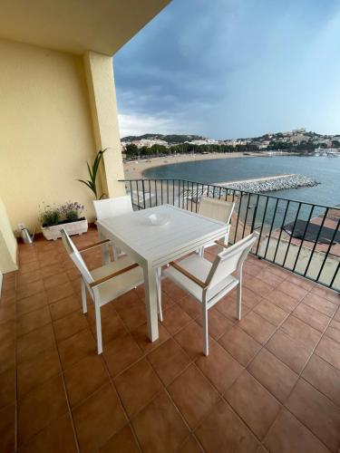 un tavolo bianco e sedie su un balcone con vista sull'oceano di Arena, exquisito apartamento con aire acondicionado en la playa a Sant Feliu de Guíxols