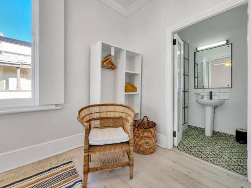 einen Korbstuhl im Bad mit Waschbecken in der Unterkunft Exquisite and Homely Apartment, Private Balcony in Kapstadt